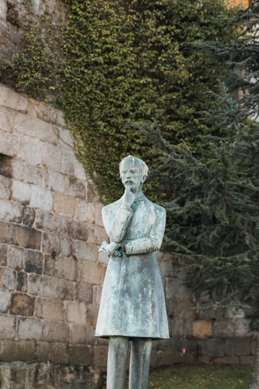 a statue with hands folded in front of brick wall