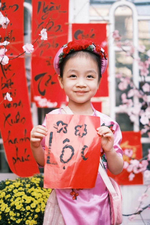 a small child holding up a piece of paper with asian writing on it