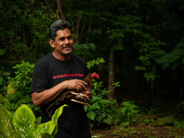 a man wearing black holding an adult turkey