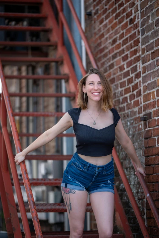 an attractive young woman leaning against a red stair case