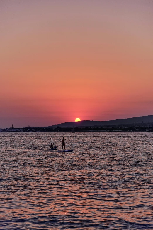 sunset on a lake with a person in the distance