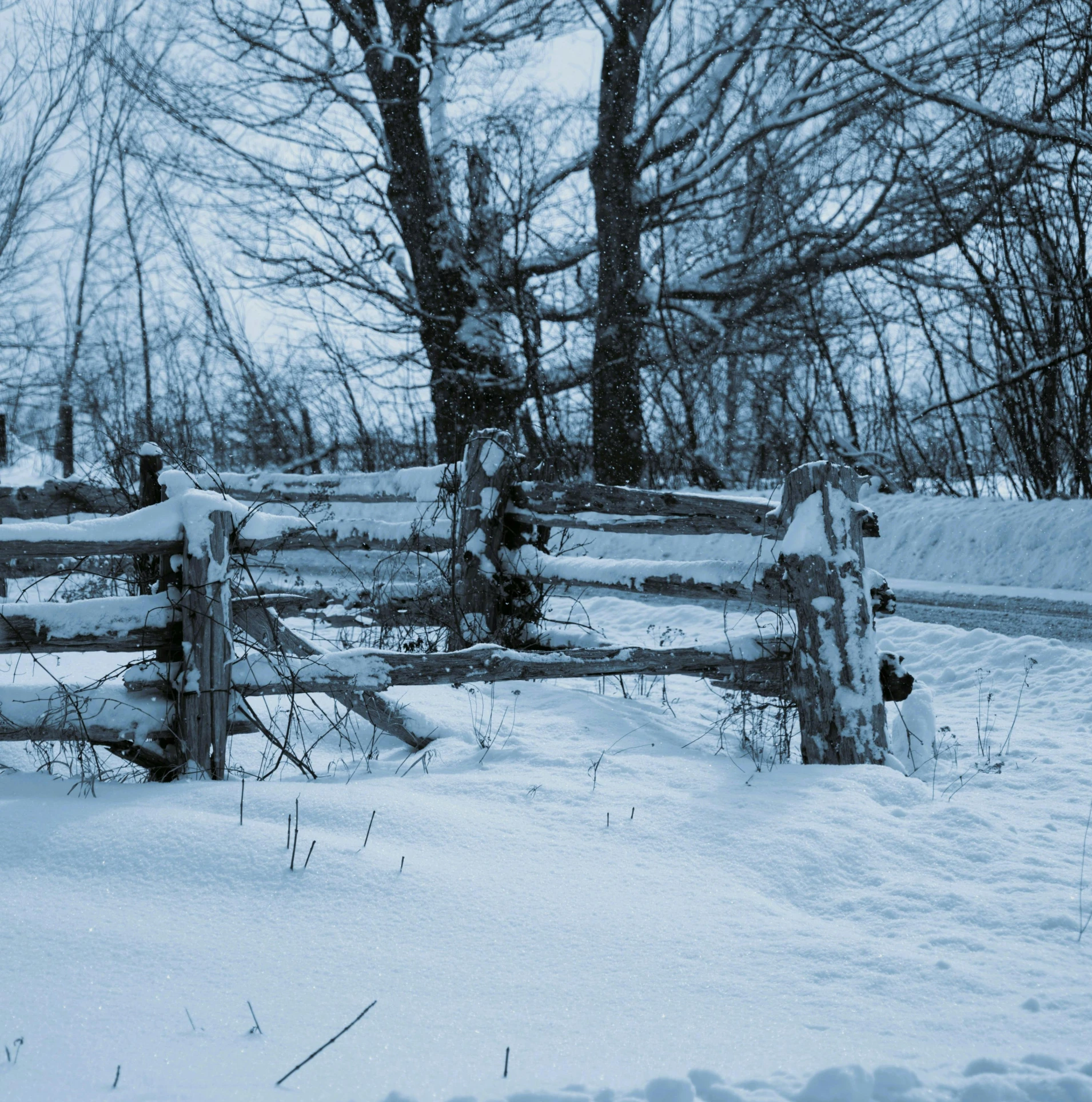 the snow is piled up along the wooden fence