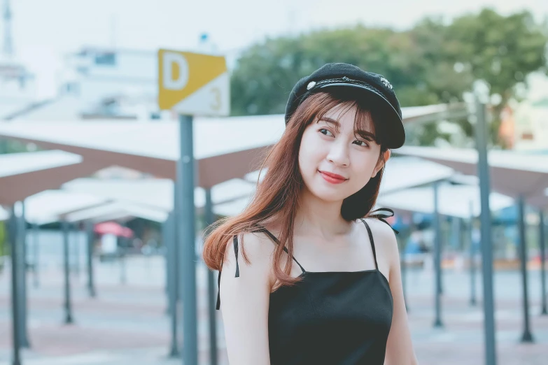 a woman in a hat, a black dress and white shoes posing for the camera