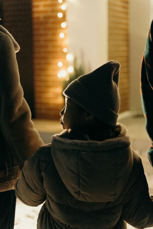 two children holding hands walking past a christmas tree