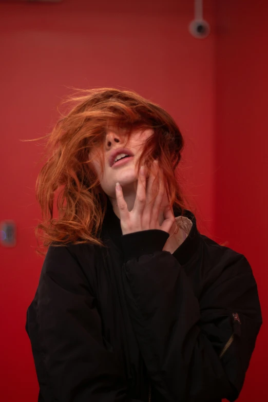 woman with red hair covers her face with hands