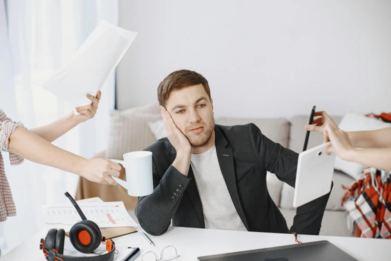 a woman holding her eye to another man's ear while he is surrounded by paperwork and other items