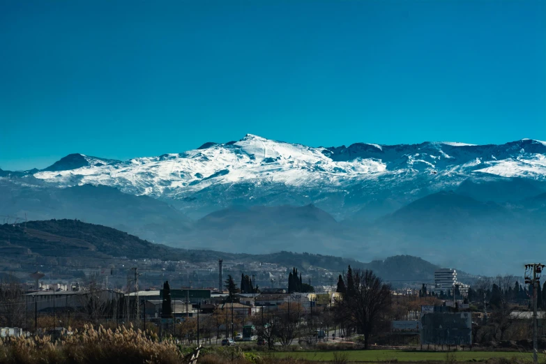 a large mountain with a snowy top and a town below