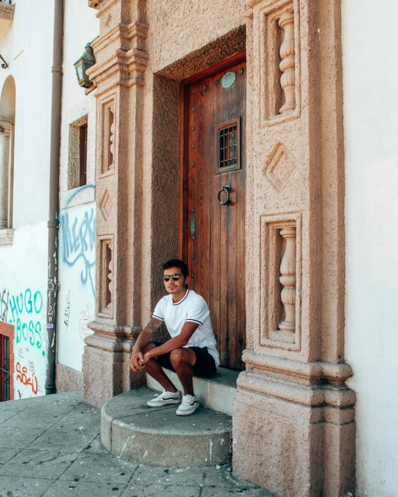 a man in a white shirt is sitting on the steps of a building