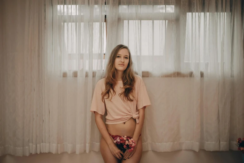 there is a woman standing next to a window with sheer curtains