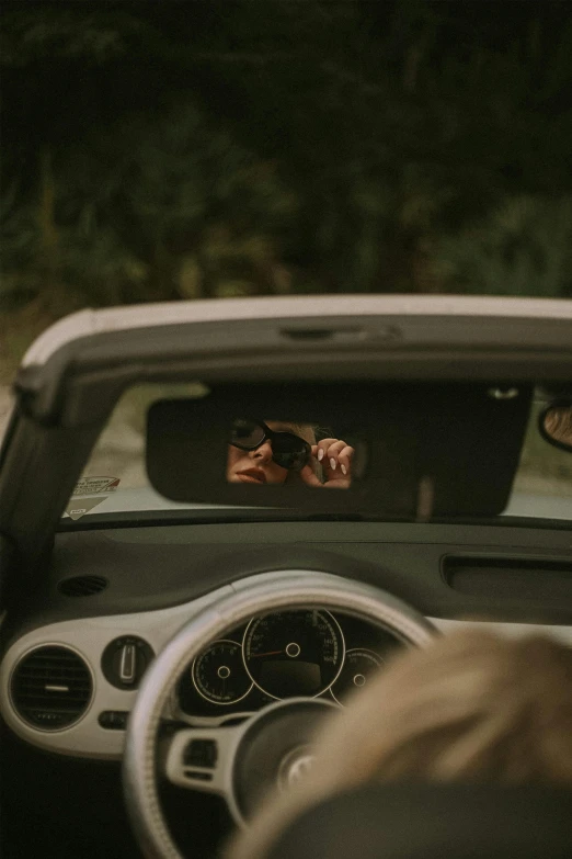 a woman's reflection in the mirror while driving a car