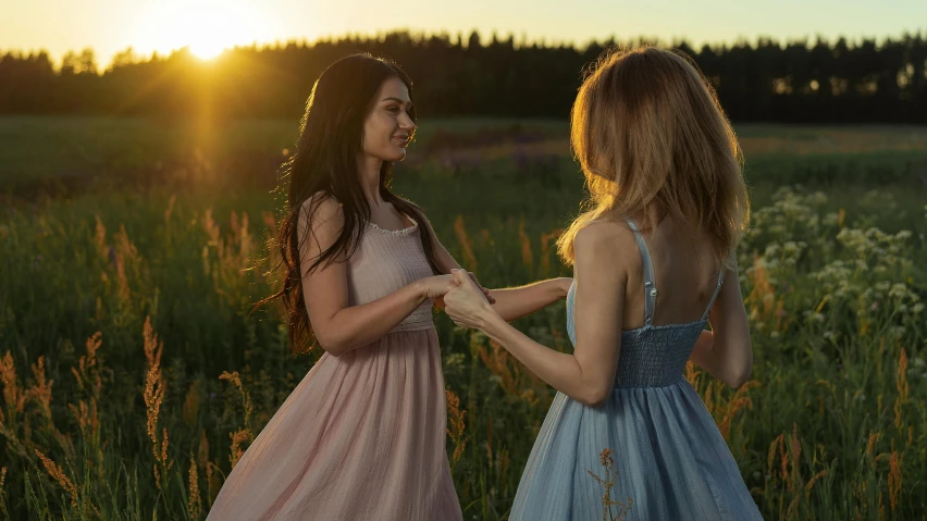 two girls are standing in the grass playing with each other