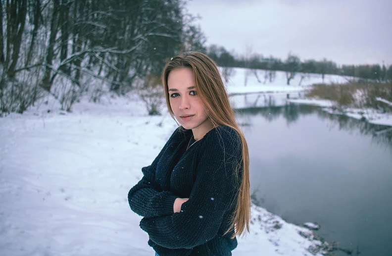 a beautiful woman posing for a picture by a lake