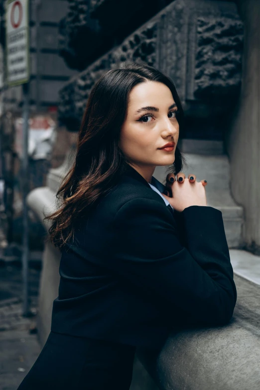 a woman wearing a black suit and holding a cell phone in her hands