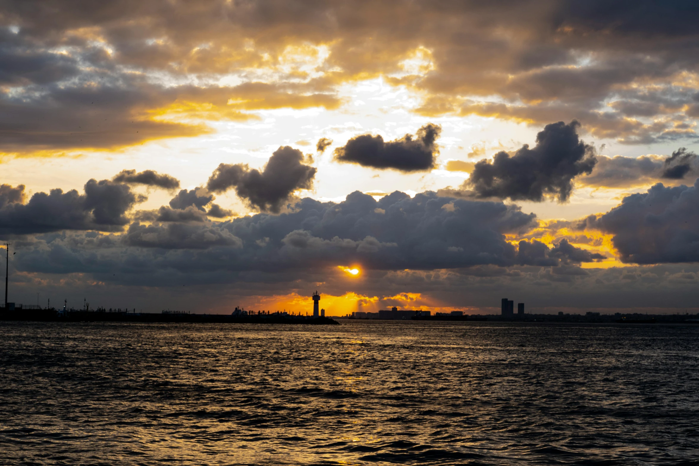 the sun is setting on a cloudy sunset over the sea