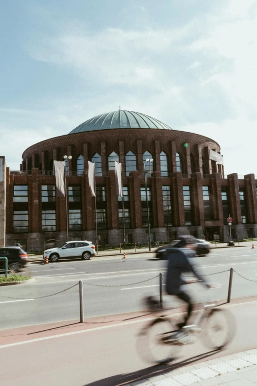 a man riding a bicycle past a brick building