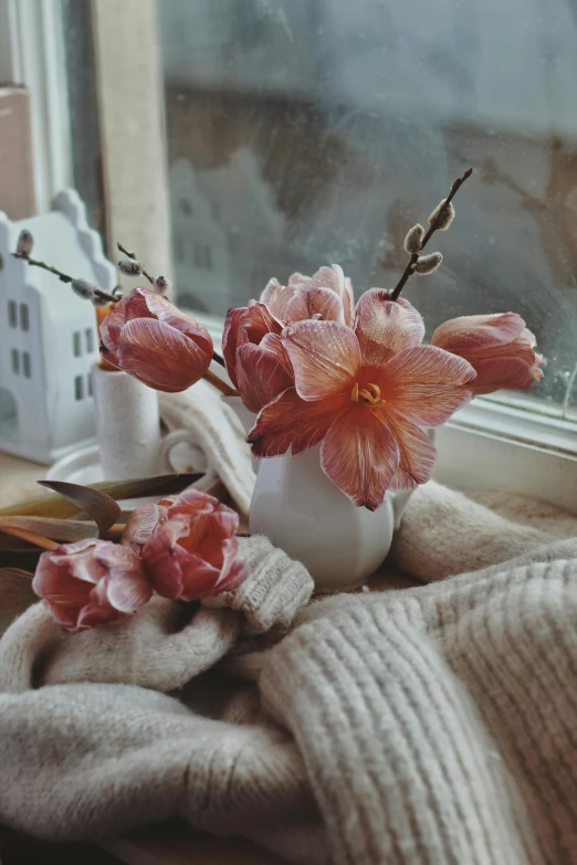two flowers are in a vase on a window ledge