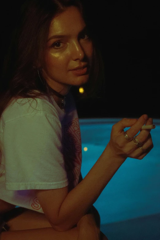 a woman sitting on the ground holding a lit cigarette