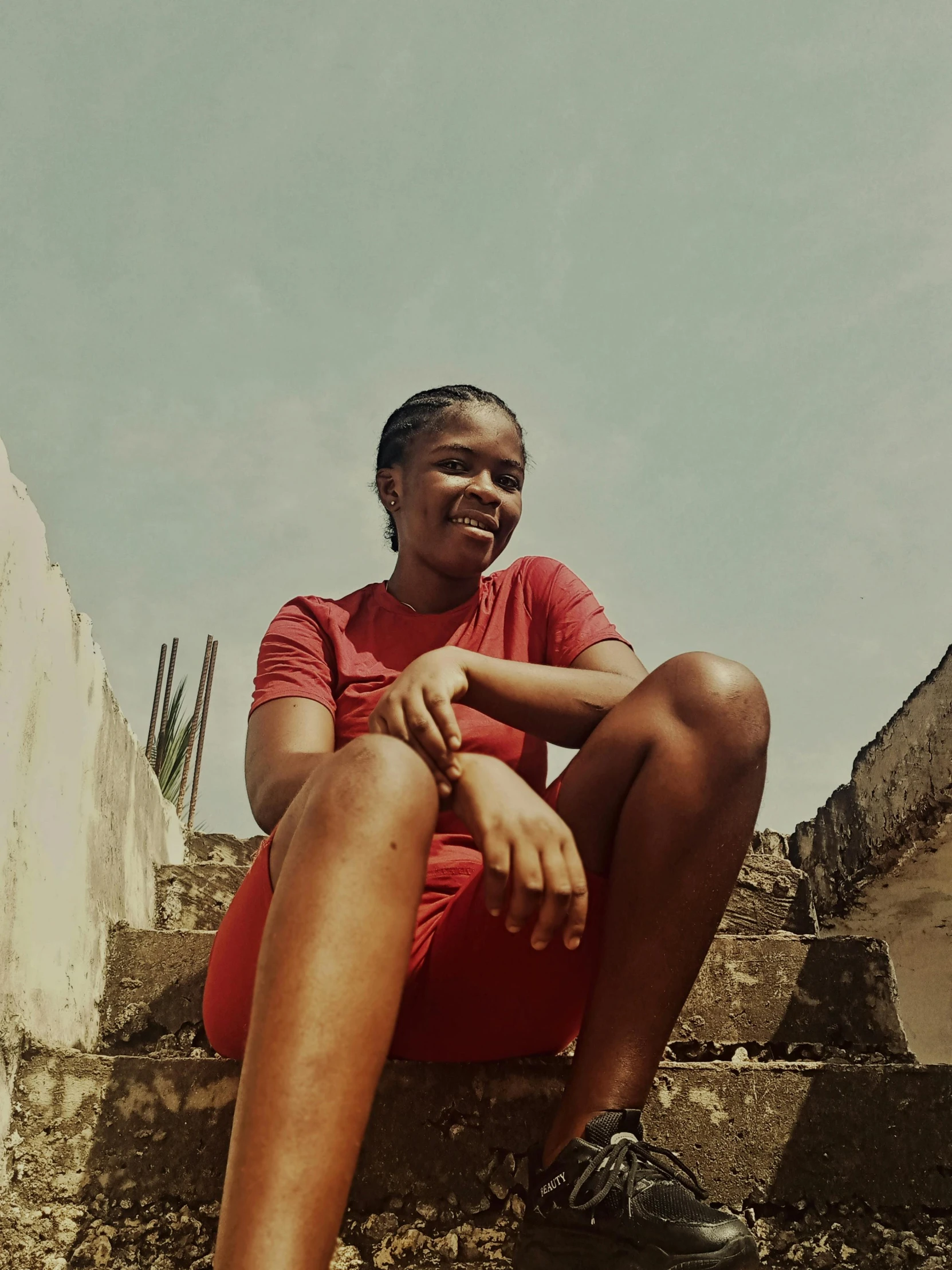 woman in red sitting down in front of some steps