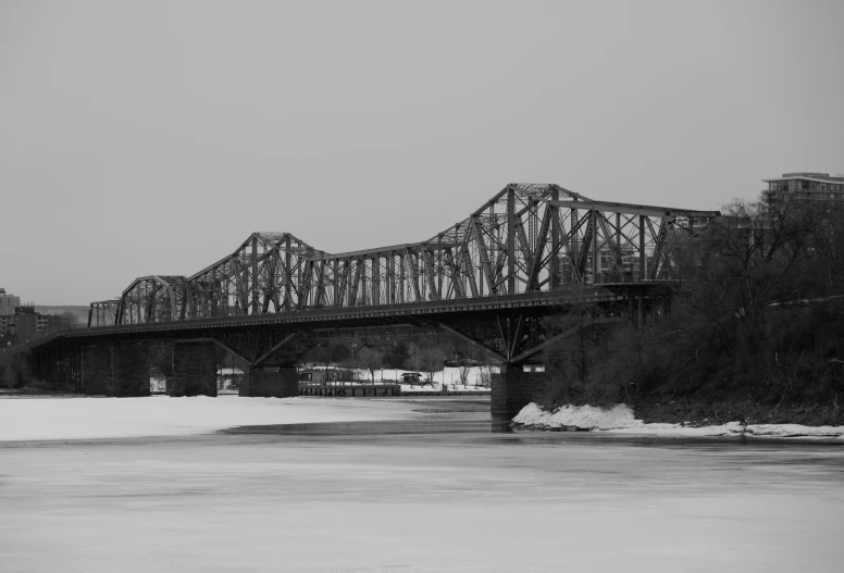 a train track bridge going over water on a cold day