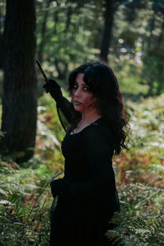 woman in black dress holding an umbrella while walking through woods