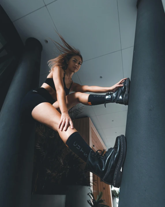 a woman in a short skirt and knee boots poses on a ledge