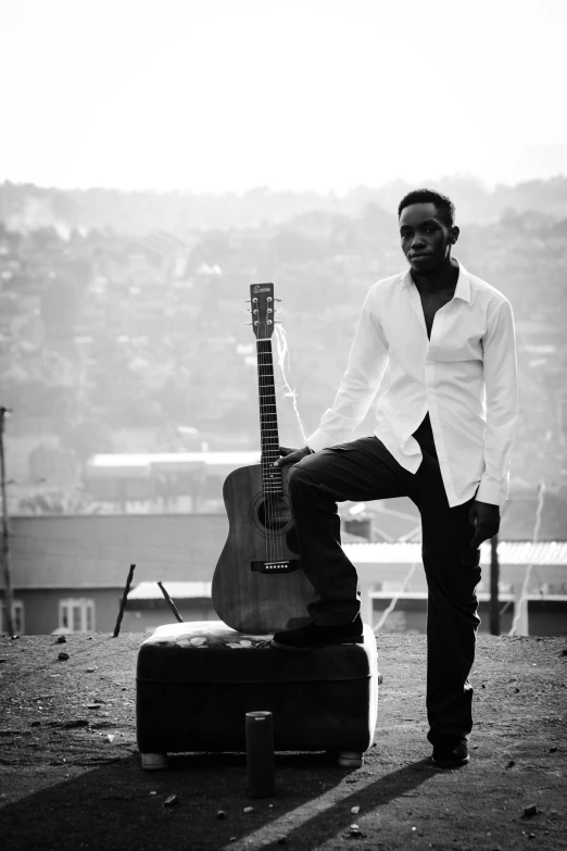 man in jeans leaning against a guitar on the roof