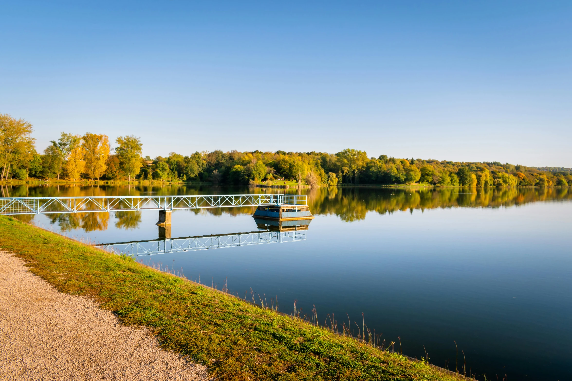 small boat tied up to dock by water with hills and trees in background