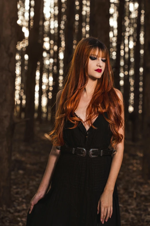 woman in a forest with her red hair blowing in the wind