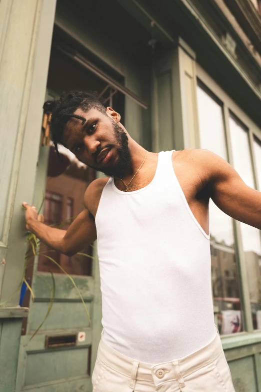 a man wearing a tank top standing in front of a door