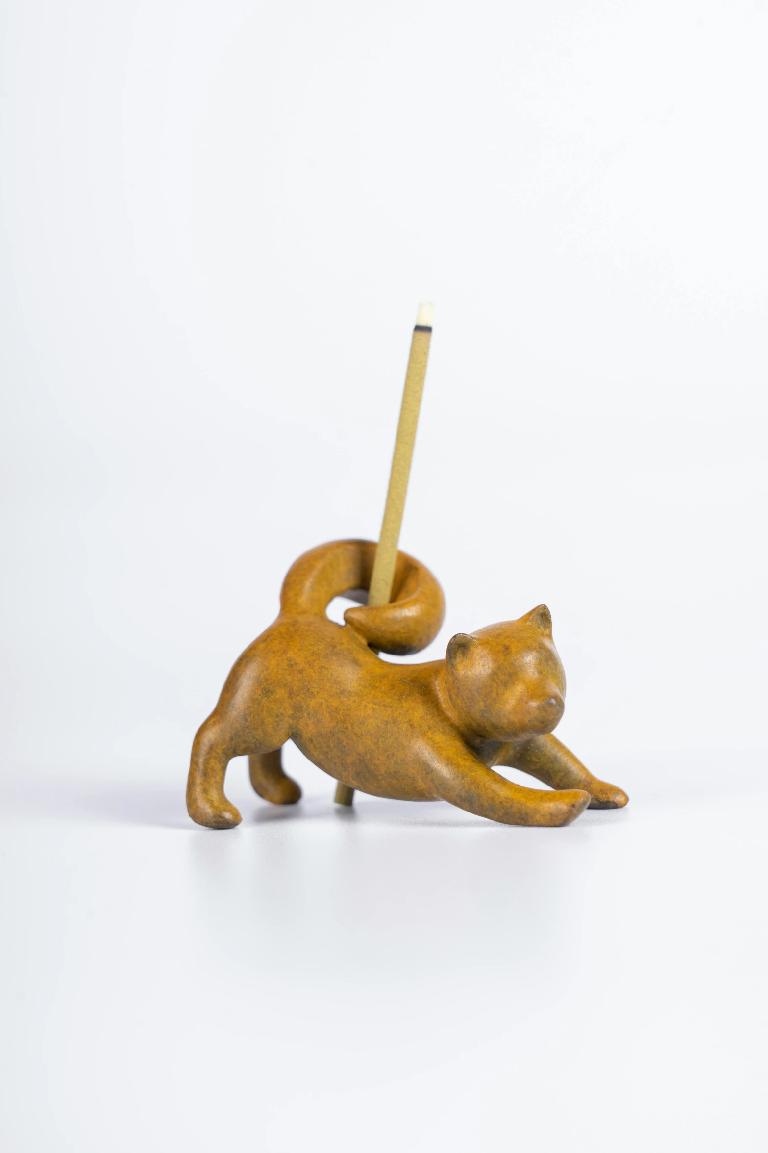 a sculpture of a cat on its back holding a stick