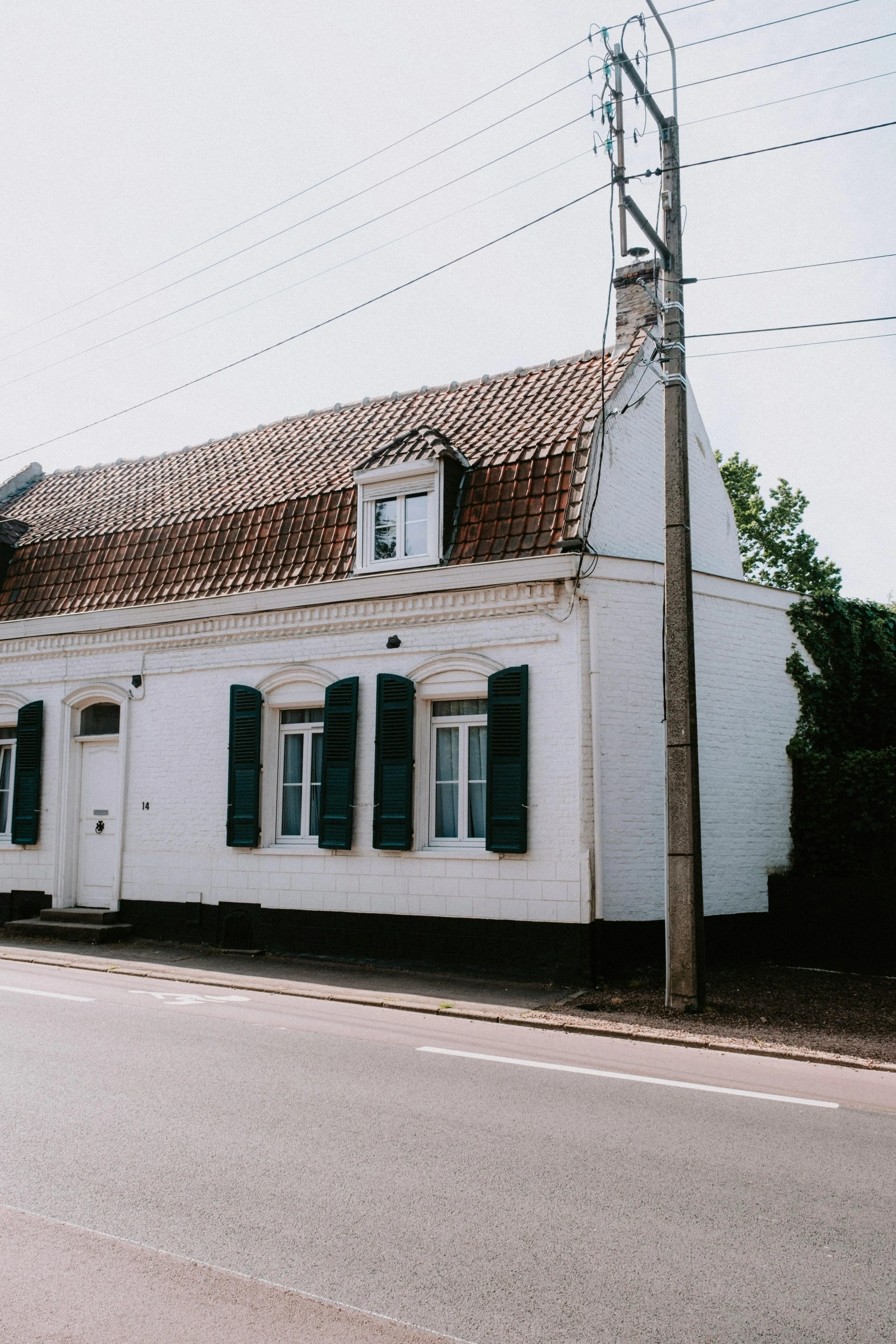 a picture of a white building with green shutters and brown shingles