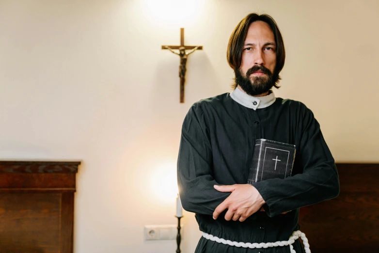 a man with his arms crossed, with the cross in the background