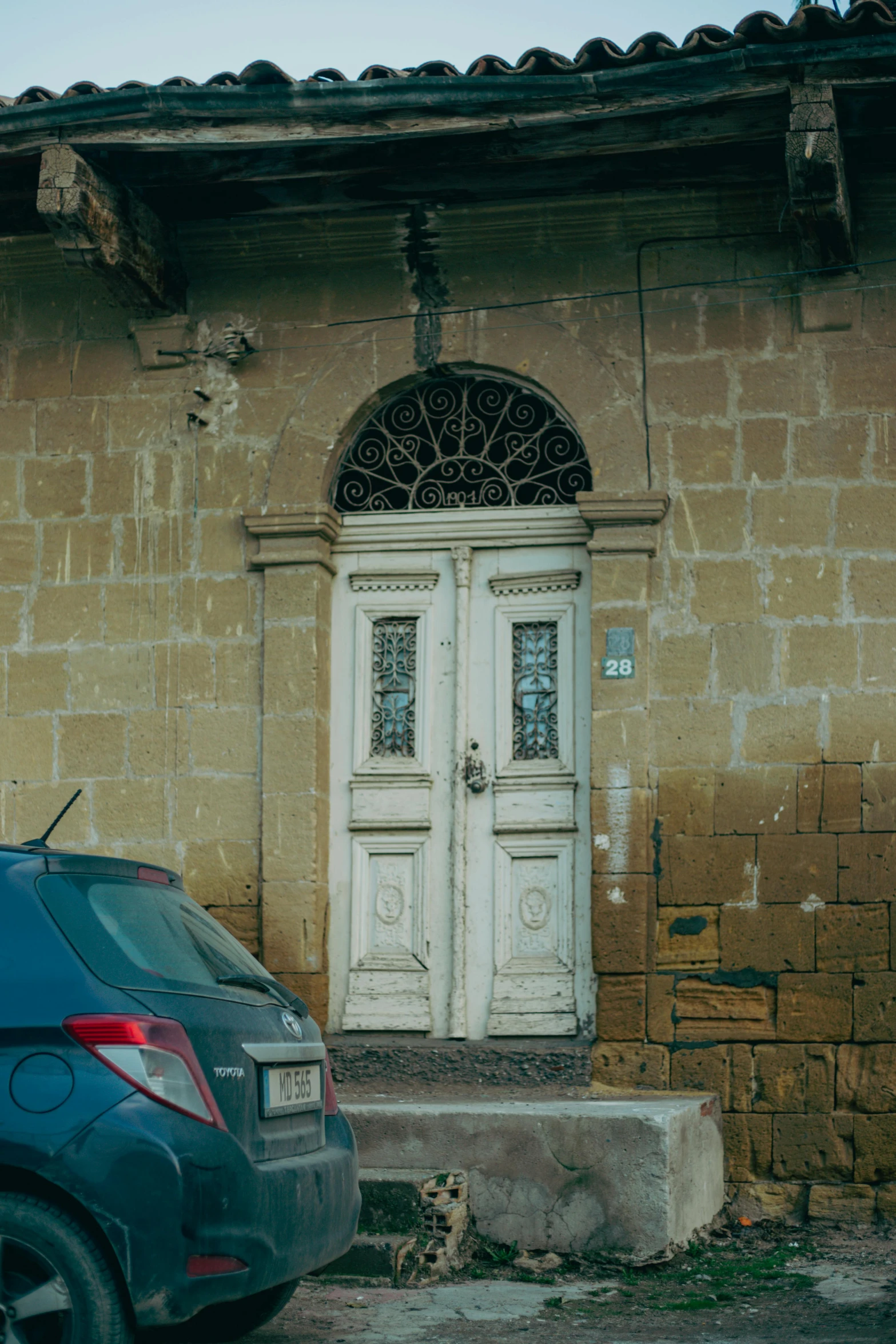 a blue car parked next to a stone wall