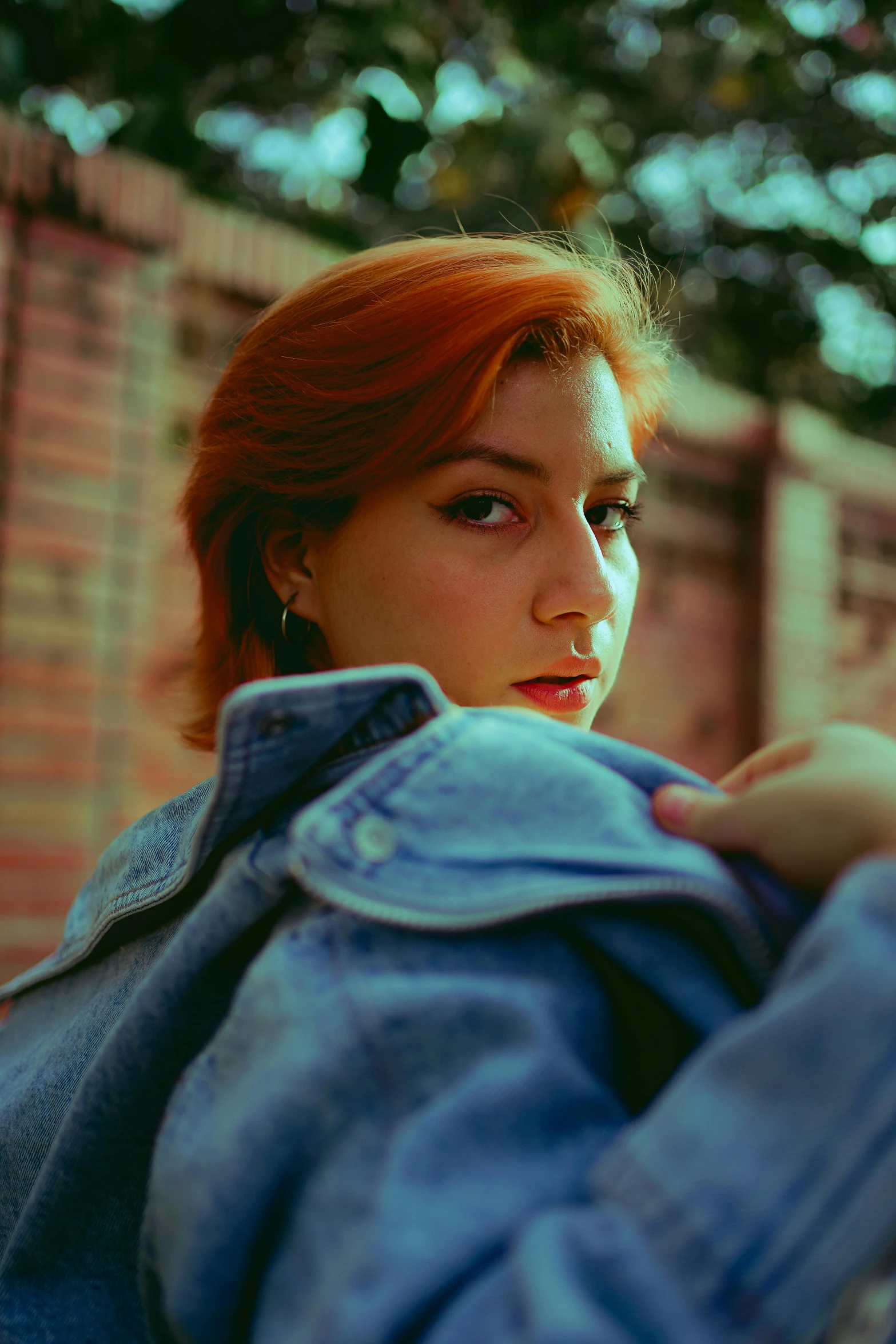 a woman leaning up against a wall with a blue jacket on