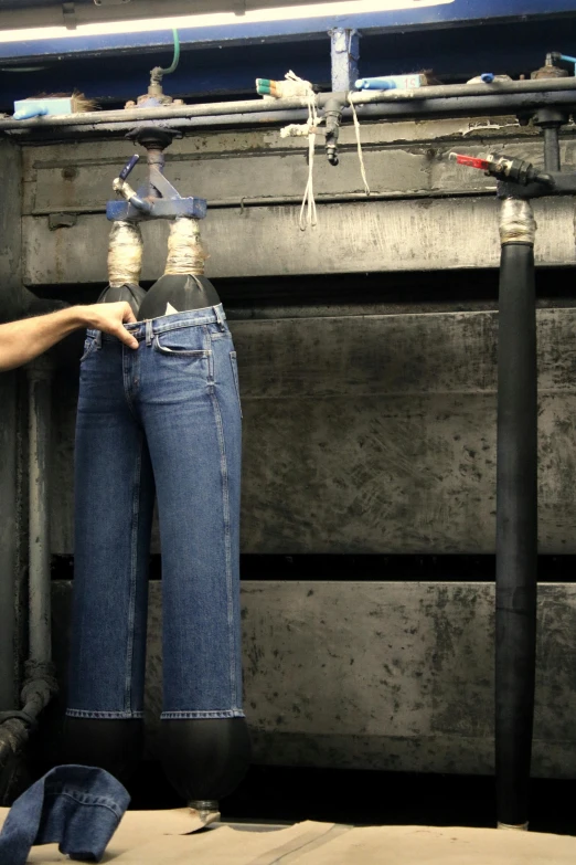 a person is pulling on the jeans that are hanging from a hook