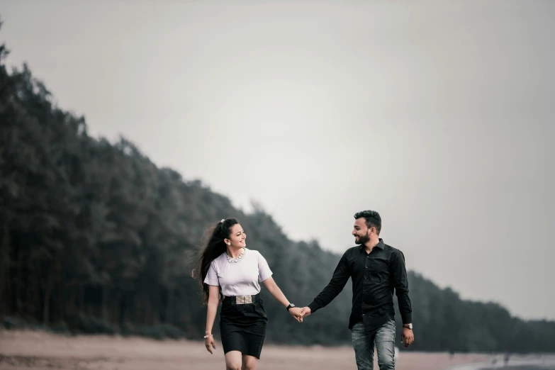 an engaged couple walking on the beach holding hands