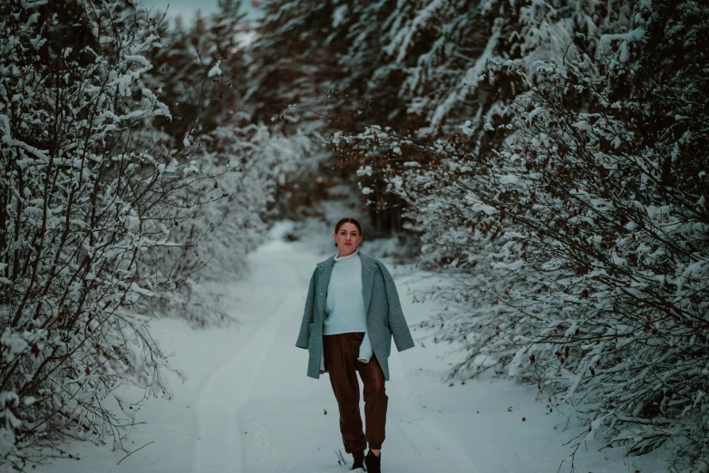 the young woman is walking on a snow path in a snowy forest