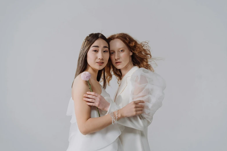 two young women in white hugging each other