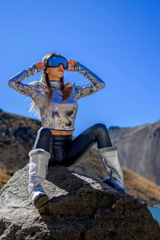 a person sitting on a large rock with her hand on their head