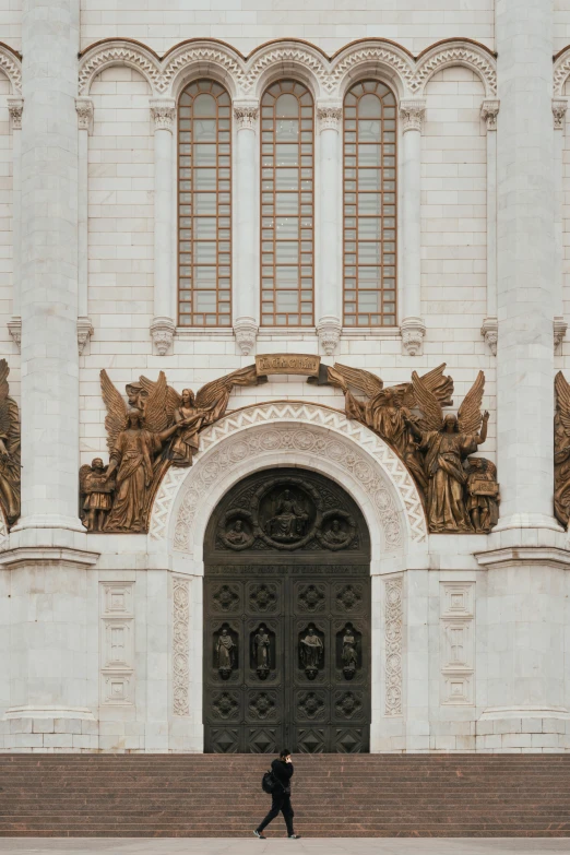 man walking towards ornate doorway in large white building