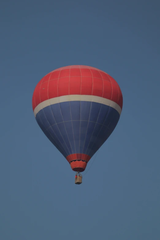 a blue, white and red  air balloon flying through a clear blue sky