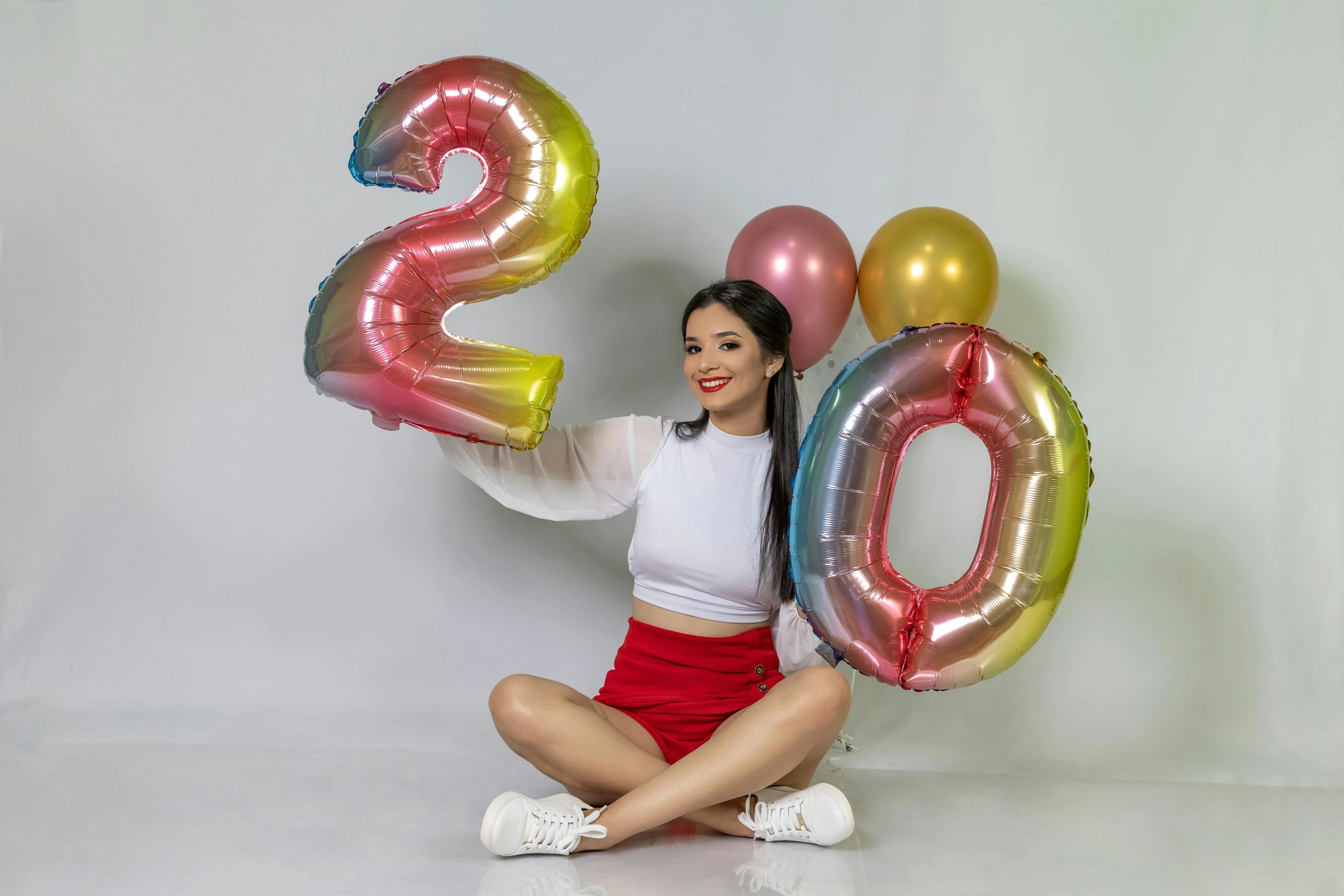 girl posing with balloons holding up the numbers