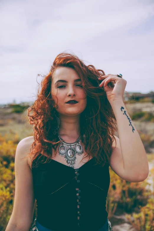 a woman wearing a black top and jewelry standing by herself