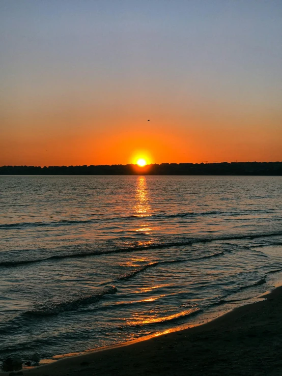 a beach with the sun setting on a beach