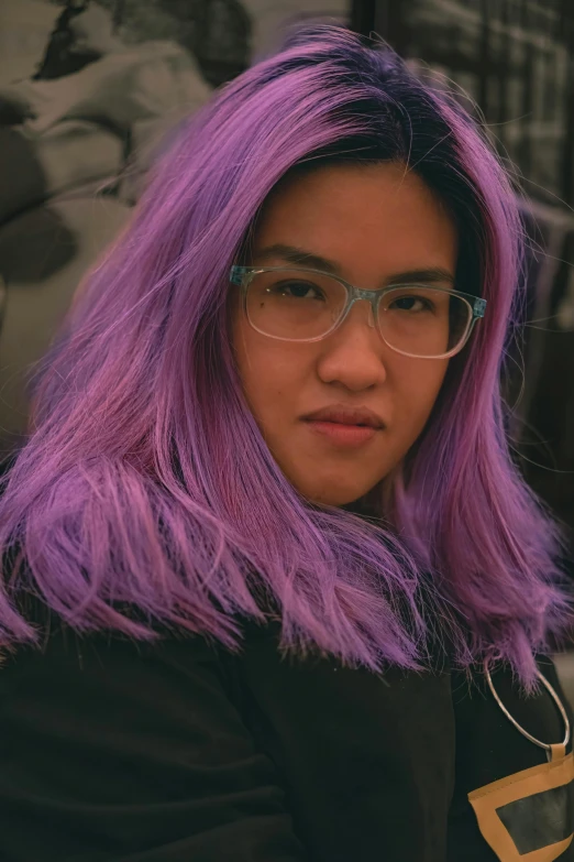 a woman with long hair wearing glasses with purple highlights