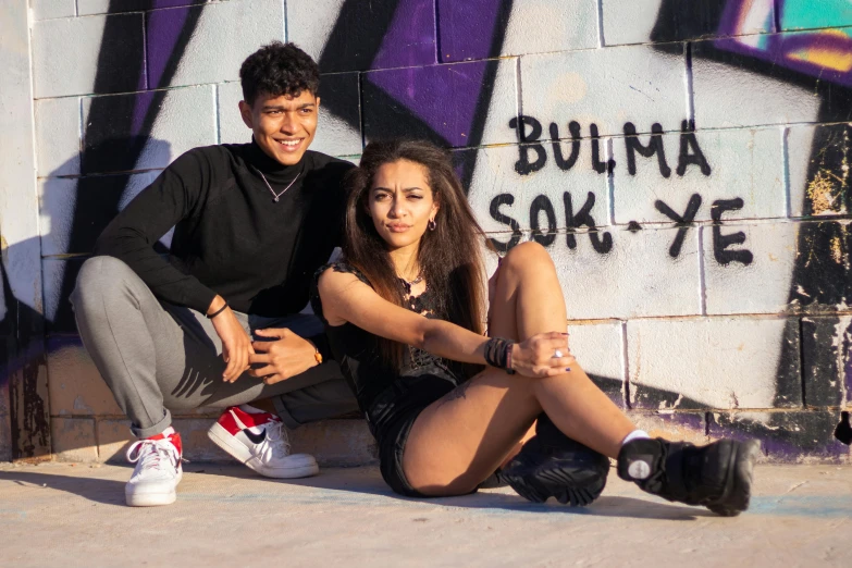 a couple poses in front of graffiti covered walls