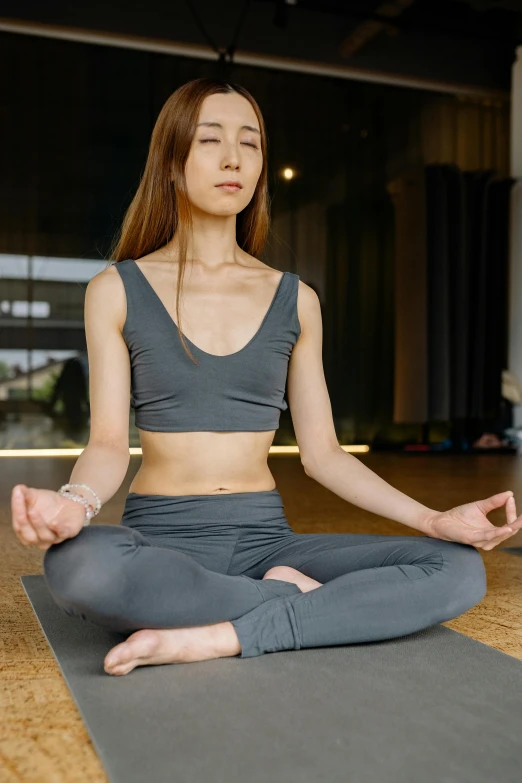 a woman sitting in a yoga pose on a mat