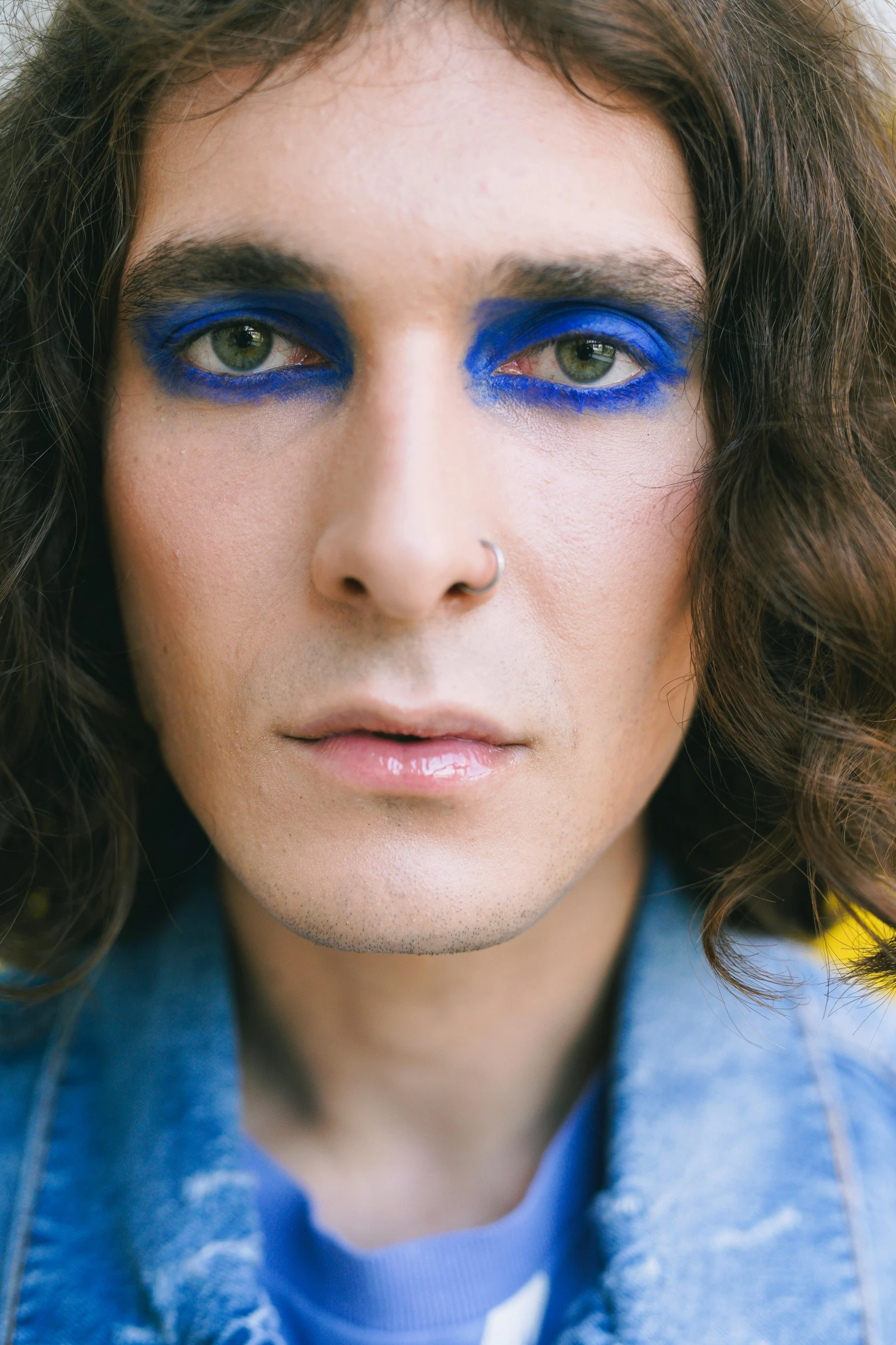 a man with long brown hair and blue eyeliners