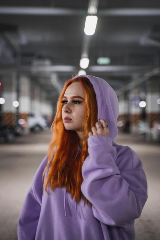 a woman with red hair wearing a purple hoodie