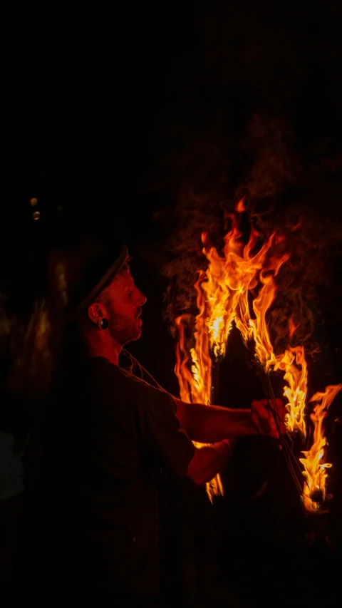 a man holding soing up to the side of a fire
